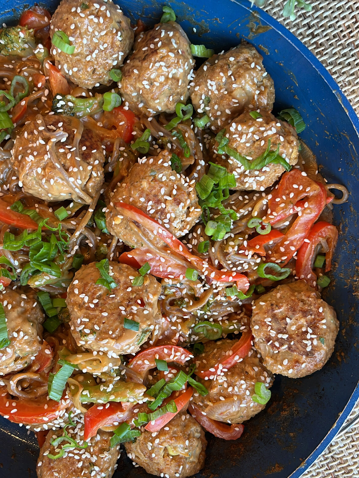 Bowl of cooked meatballs garnished with sesame seeds.