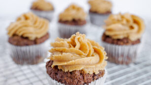 Six chocolate peanut butter cupcakes with peanut butter frosting on a cooling wire rack