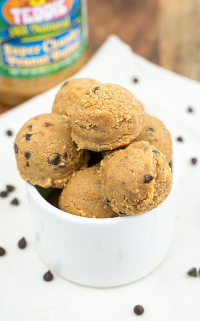 Peanut butter cookie dough balls on a white napkin in a small bowl on a white linen napkin