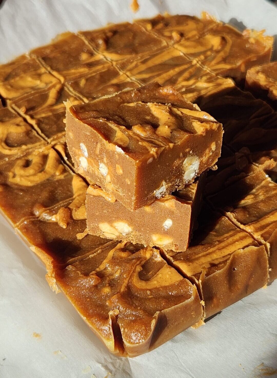 Two pieces of fudge stacked together on parchment paper.