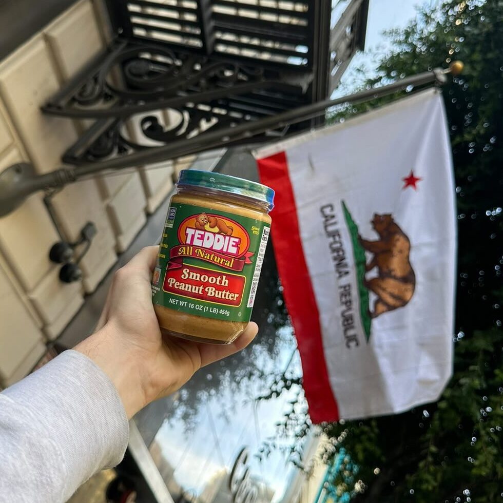 Teddie Peanut Butter jar held in front of a California Republic flag