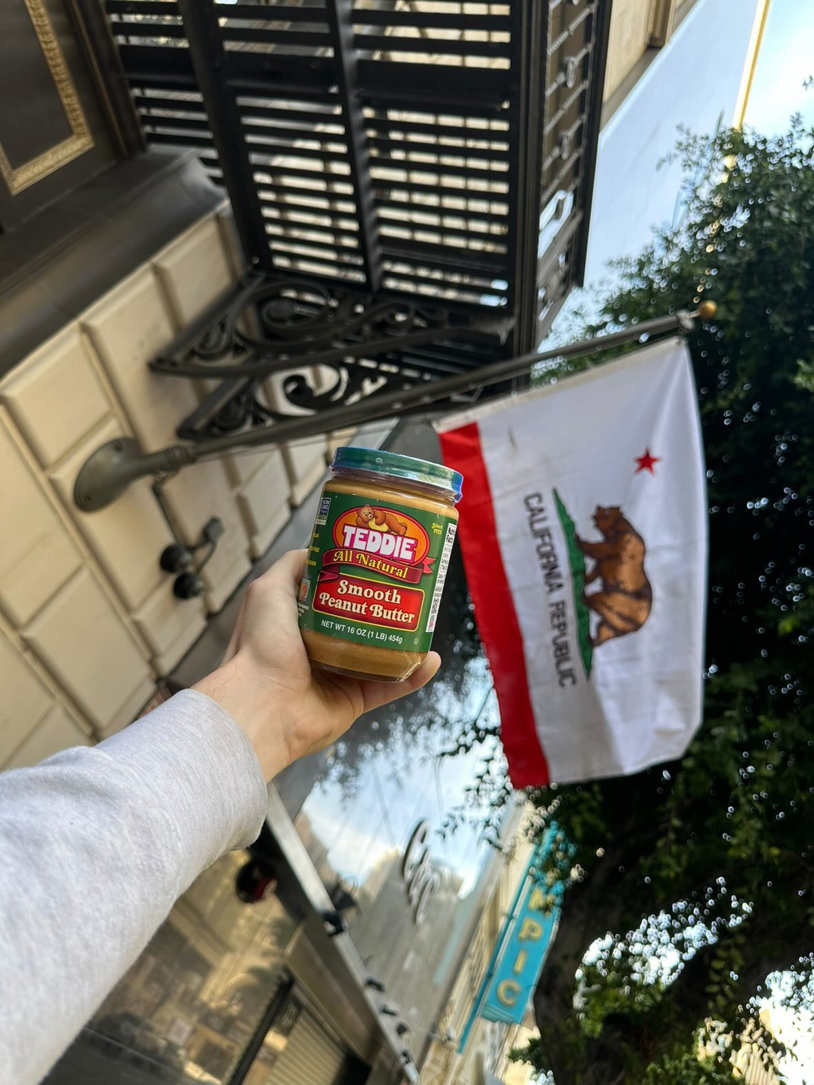 Teddie Peanut Butter jar held in front of a California Republic flag
